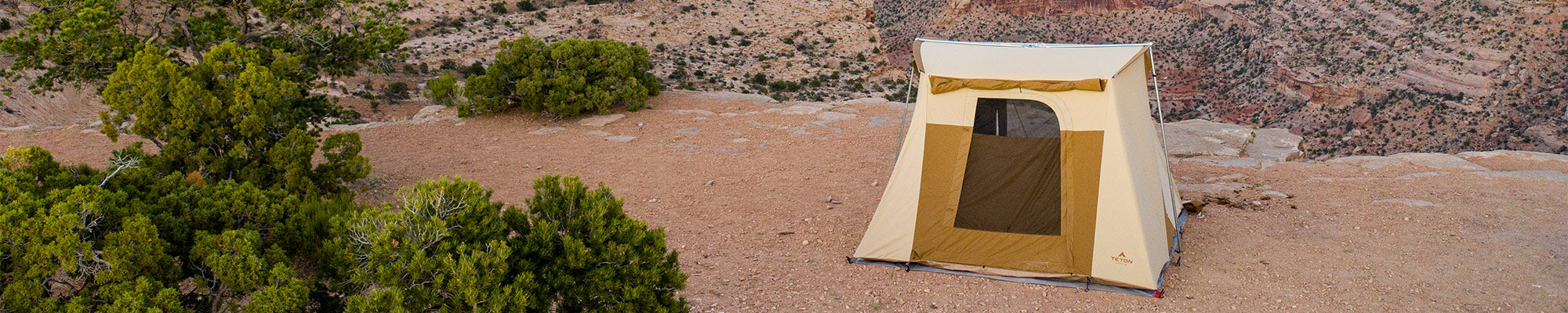 A lone TETON Sports Mesa Canvas Tent sits atop a rocky acrop in the desert.